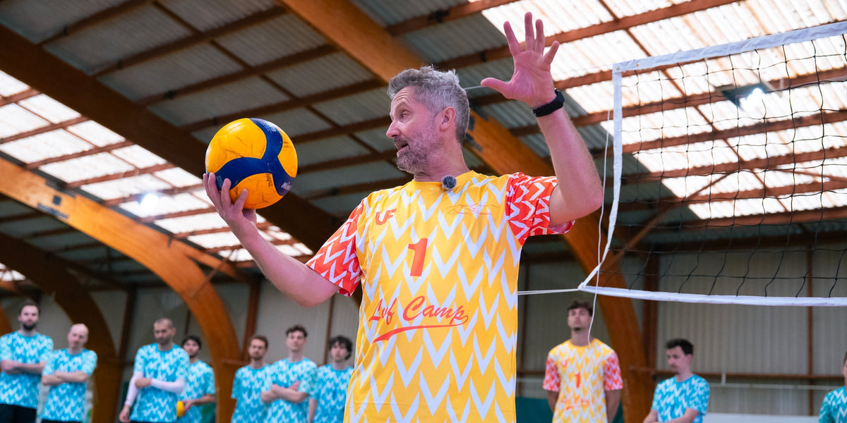 Homme avec t-shirt LVF collection Chinenyeze tenant un ballon de volleyball devant une foule équipée en LVF